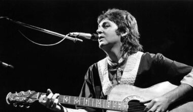 Paul McCartney playing acoustic guitar onstage