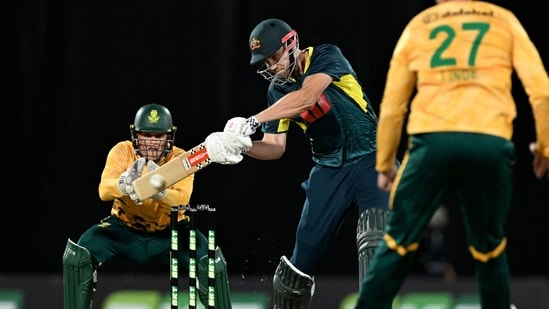 Cameron Green (C) hits a delivery as South African wicketkeeper Ryan Rickelton (L) looks on during the first T20 international cricket match between Australia and South Africa(AFP)