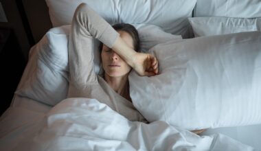 a woman lays in bed with her arm over her face