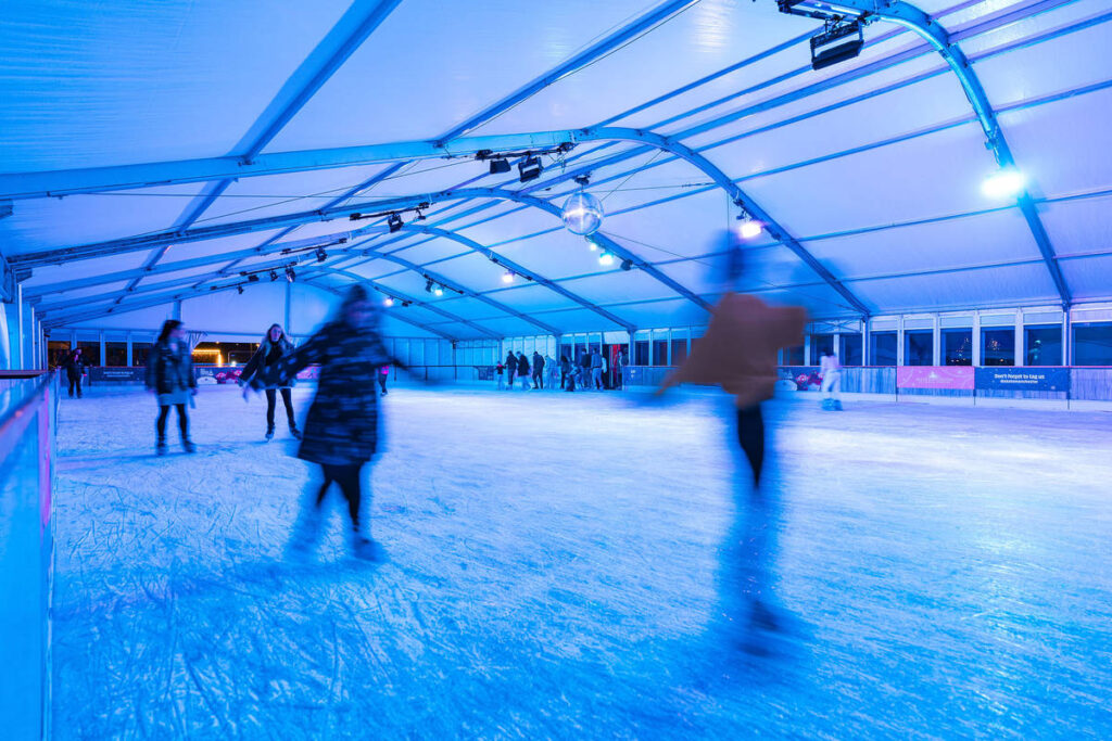 people skating inside skate manchester ice rink with blue lights