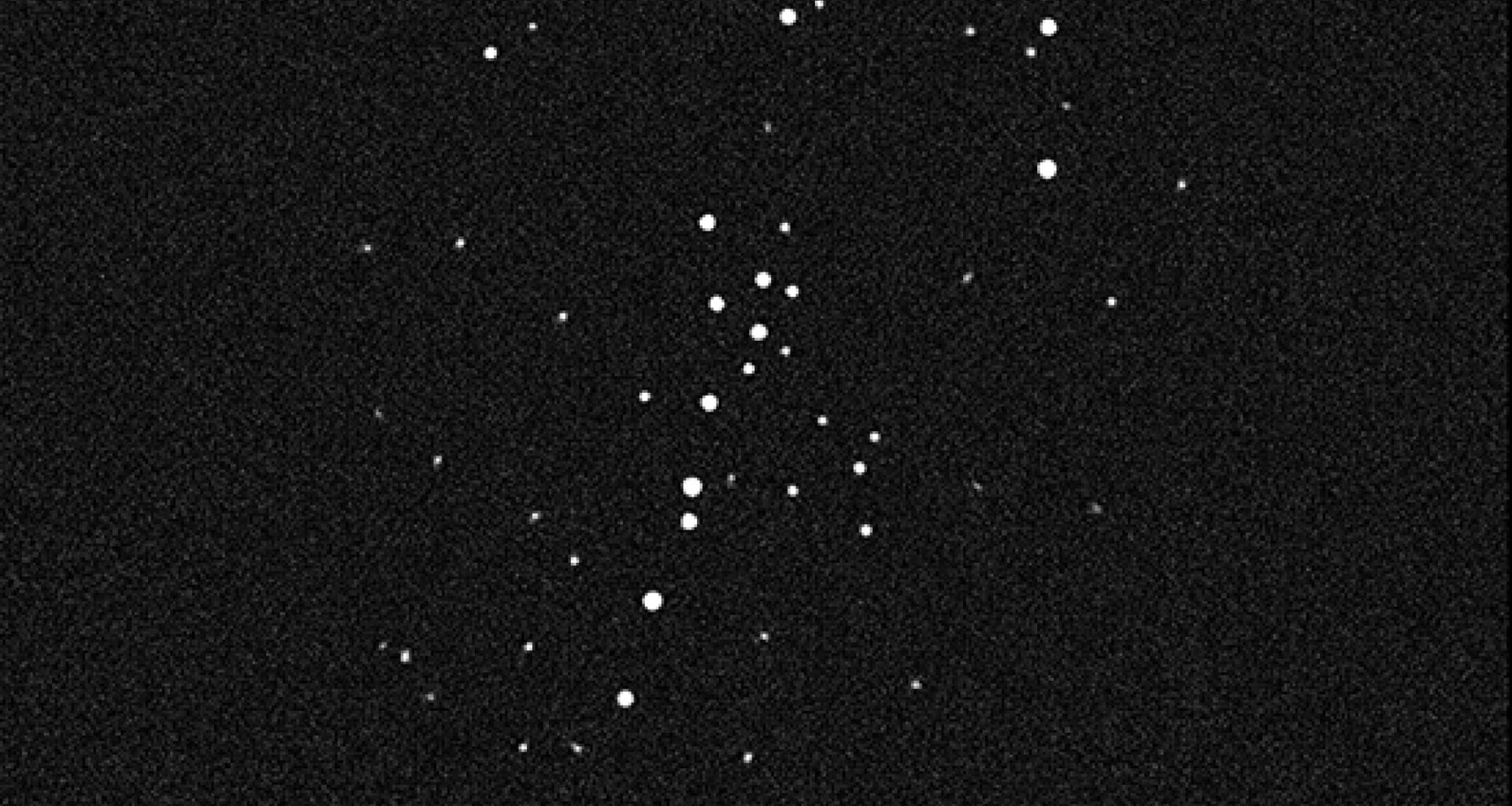 black and white image of deep space showing several dozen stars, which appear as white dots of varying sizes
