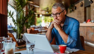 Mature man using laptop in a cafe, looking annoyed