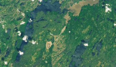 A photo of Earth from space shows its green landscape with a large brown shape in the middle where a drained lake sits