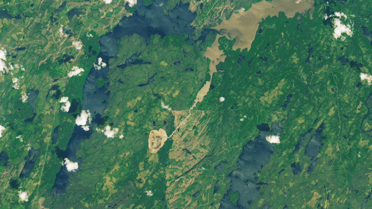 A photo of Earth from space shows its green landscape with a large brown shape in the middle where a drained lake sits