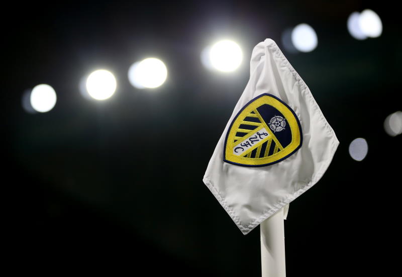 A corner flag with the Leeds United badge on it is seen in the dark with floodlights in the background