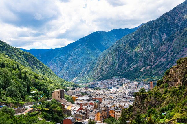 Houses and buildings in a valley in Andorra la Vella, surrounded by tall green mountains.