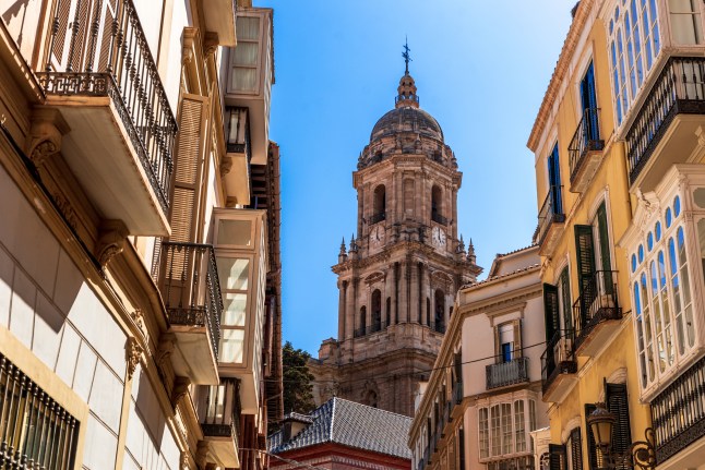 Malaga cathedral tower seen between buildings on a sunny day in Malaga, Spain.