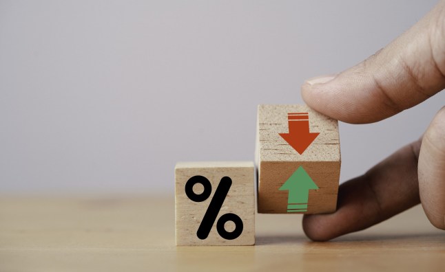Hand flipping wooden cube block to change between up and down with percentage sign symbol for increase and decrease financial interest rate and business investment growth from dividend concept.
