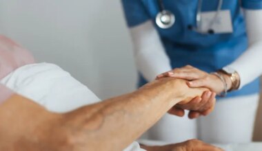 Close-up of caregiver holding senior client hand.