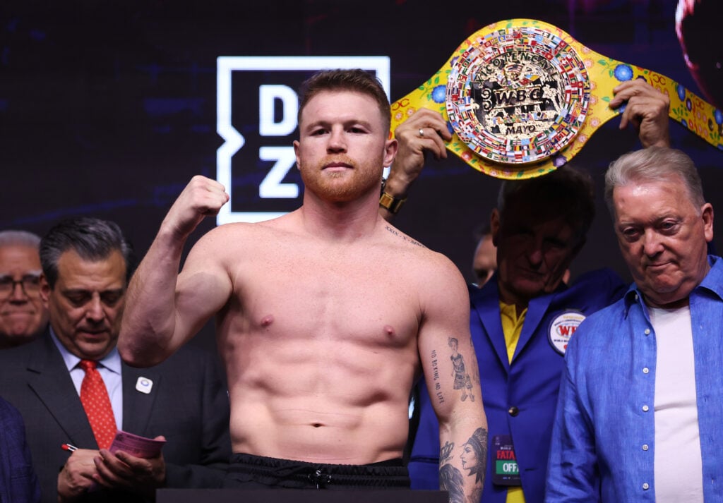 Canelo Alvarez flexes fist at weight in with belt in background