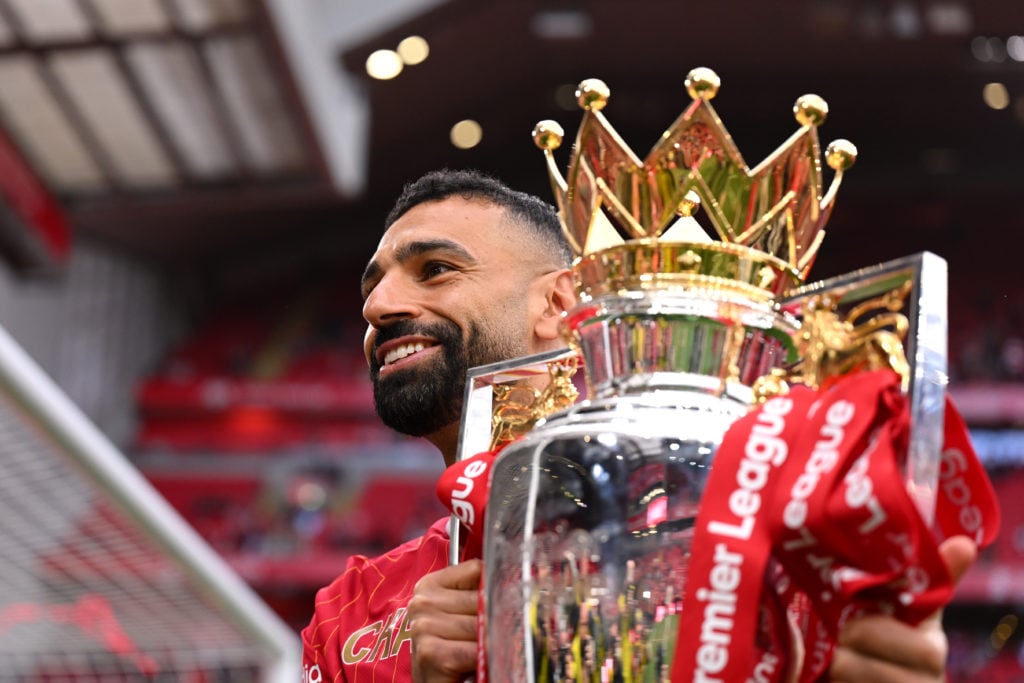 Mohamed Salah poses with the Premier League trophy in front of Liverpool fans.