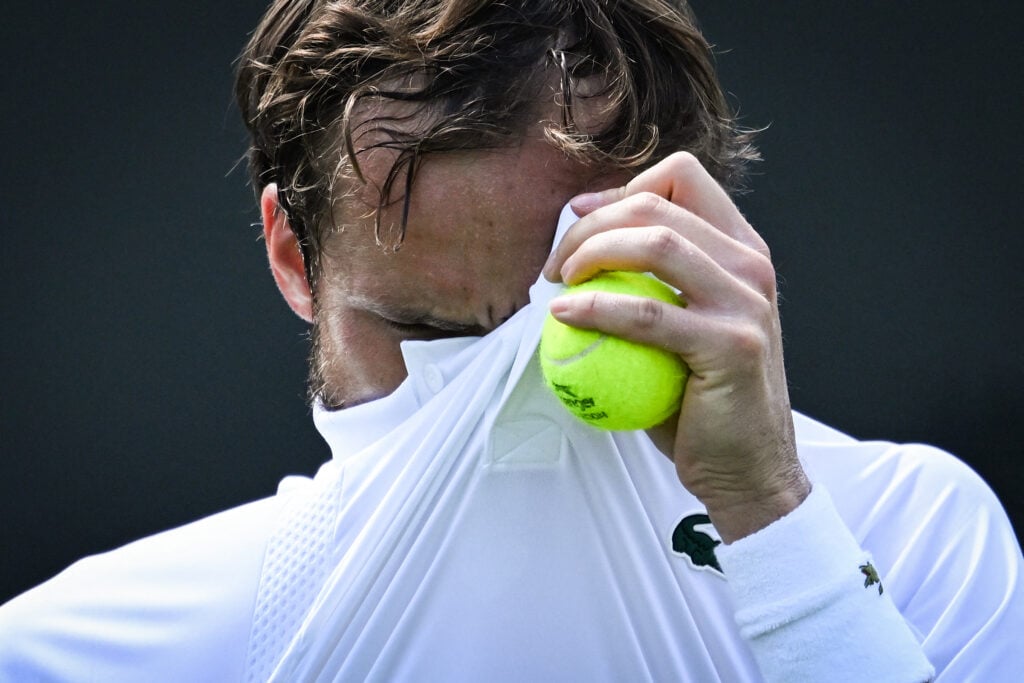 Daniil Medvedev wipes his face during his first-round defeat at Wimbledon in 2025