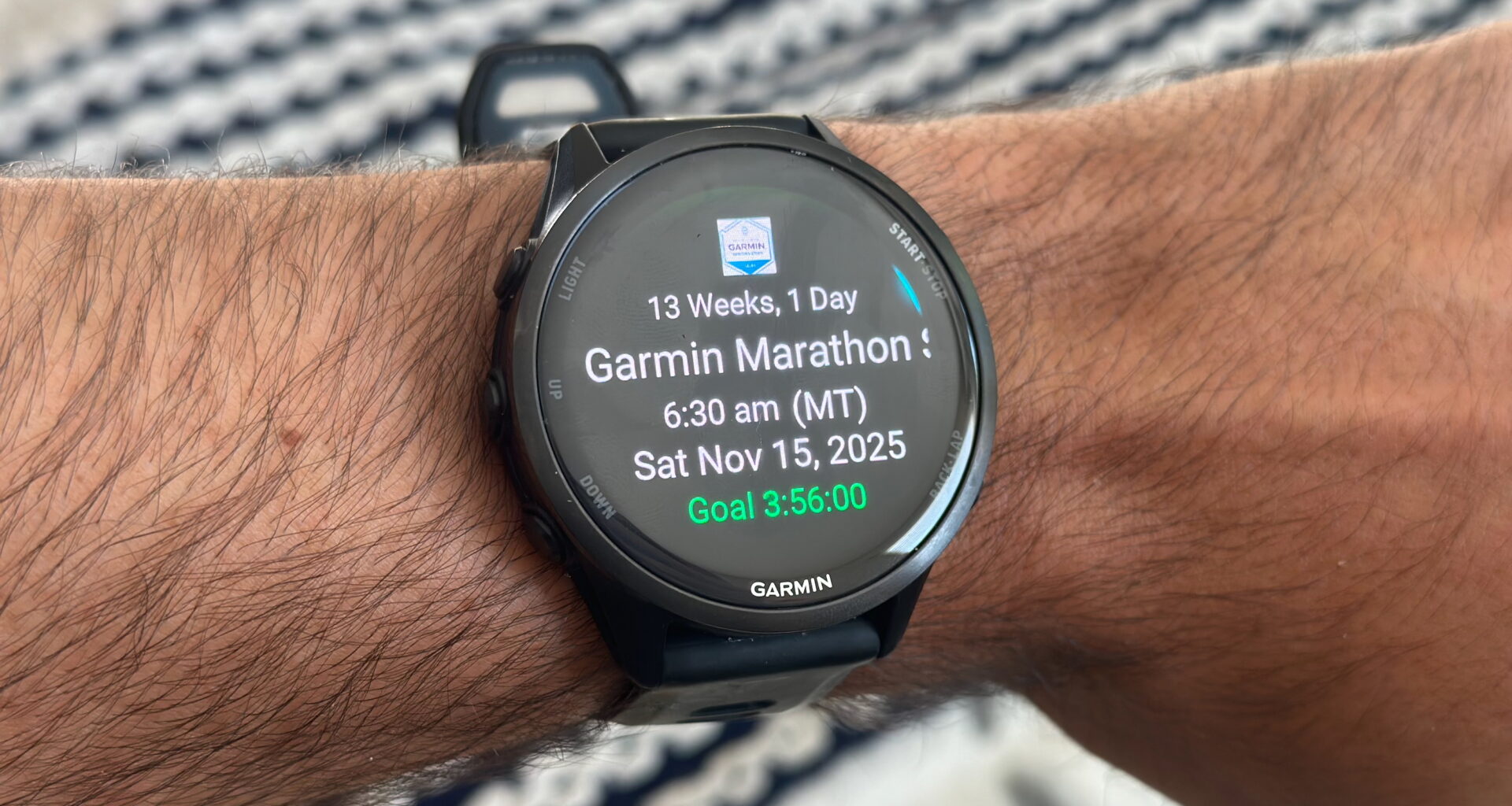 The Garmin Forerunner 970 on the author's wrist, showing the Primary Race widget with the Garmin Tucson Marathon time, date, weeks until the event, and goal time.