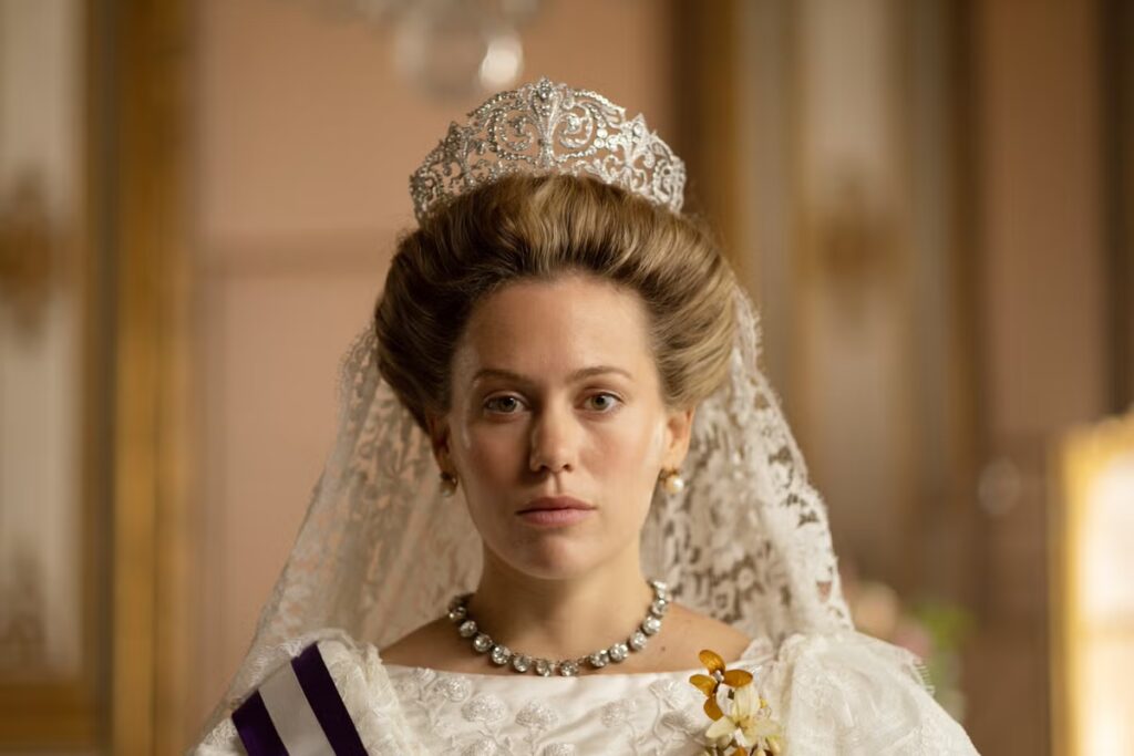 Kimberley Tell as Queen Victoria Eugenia of Spain in TV show Ena. She wears a wedding dress and huge tiara.
