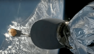 The Earth is seen in the background, a cylinder is seen falling toward it, and in the foreground there is shiny material connected to what seems to be an engine.