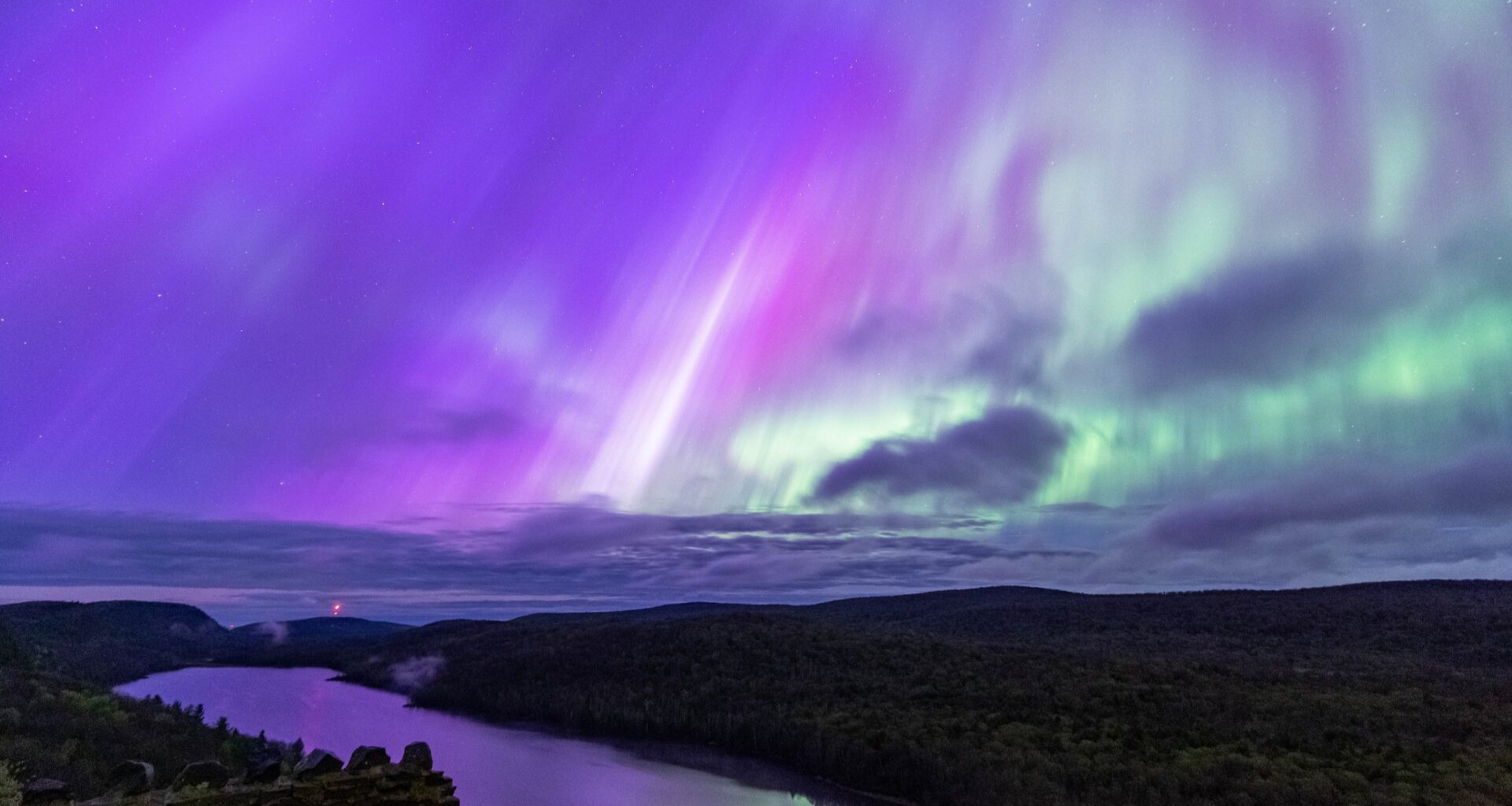 northern lights appear as ribbons of purple and green light over Carp Lake, Michigan, USA