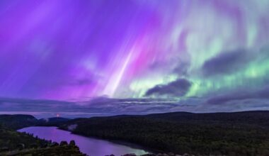 northern lights appear as ribbons of purple and green light over Carp Lake, Michigan, USA