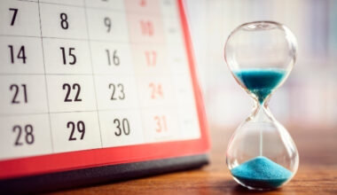 Page of calendar next to sand timer to symbolise passing of time