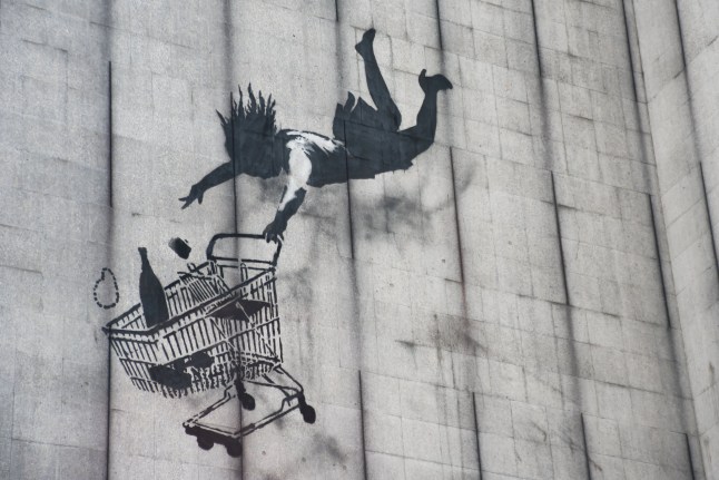 Banksy's Falling Shopper is pictured in Central London on August 4, 2017. Falling Shopper is a stencil art piece Banksy painted some meters above street level on the side of a large, disused office building, back in 2011. Showing a well off woman clutching her shopping trolley filled with groceriesm while plummeting from a great height, Falling Shopper was purposely placed in upmarket, high-end shopping district of Mayfair, part of London with a high density of upscale shops. (Photo by Alberto Pezzali/NurPhoto via Getty Images)