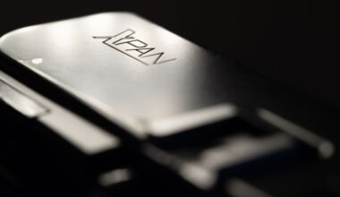 Close-up of a metallic camera part with the engraved logo "XPAN," highlighting its smooth, reflective surface and blurred background.