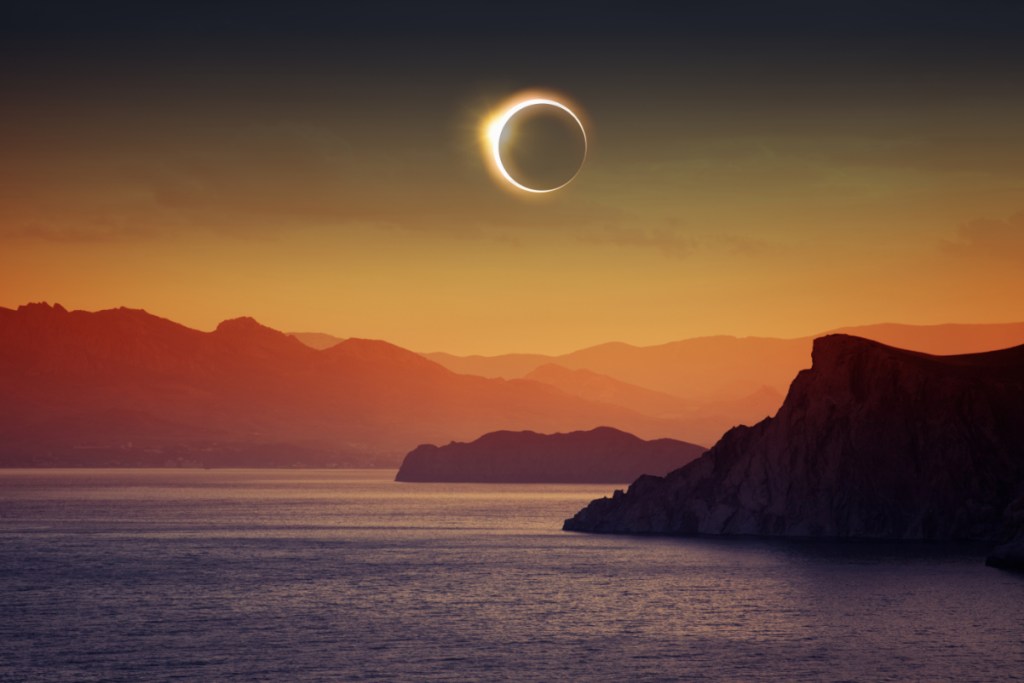 A photo illustration of a total eclipse above a scenic, rural, water-based tourism destination in Europe.