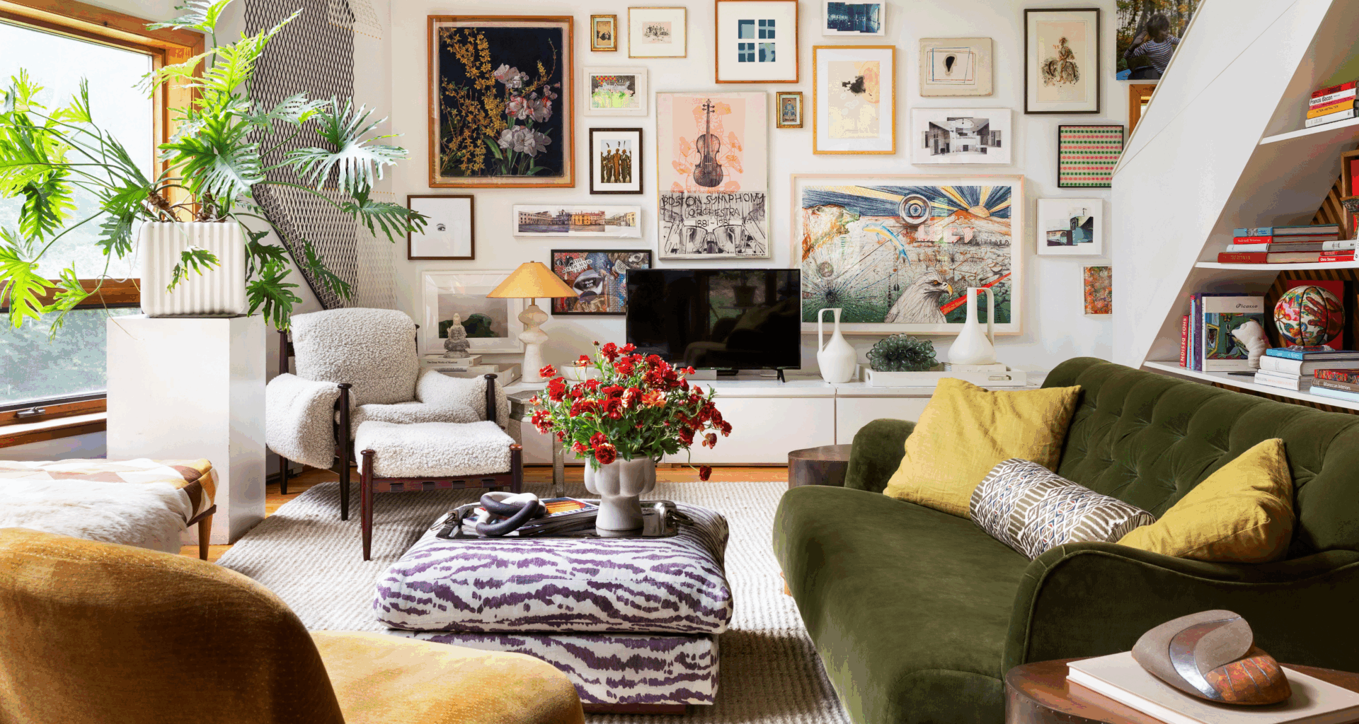 Eclectic sun drenched living room featuring a zebra patterned ottoman and cozy upholstered sofas and chairs. The far wall features a credenza styled with various sculptural objects. Above, there is a gallery wall of assorted paintings and prints.