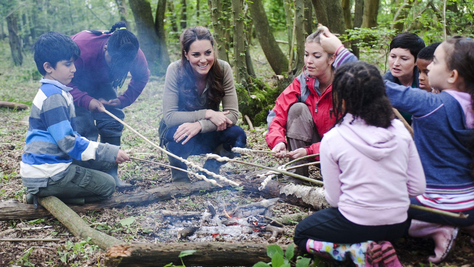 Kate Middleton sits around a camp fire with children