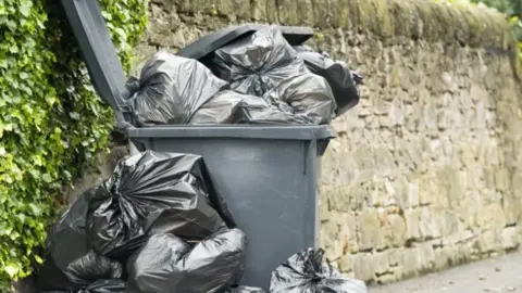 Getty Images Black bins with black bags overflowing 
