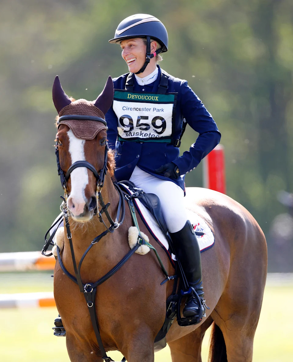 Zara Tindall wearing an equestrian outfit and helmet sitting on a horse and smiling