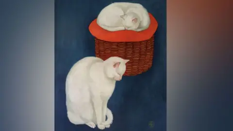 Robjn Cantus/Derbyshire PFS A picture by C Brooke showing two white cats against a deep blue background. The cat on the left is sitting up, with its head down and its tail around its front paws. The second cat is behind it to the right and is curled up on a red cushion on top of a wicker basket. 