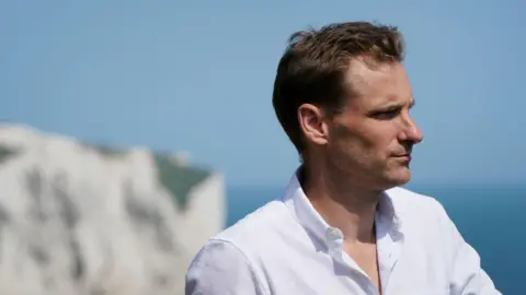 PA Media Chris Philp in a white shirt. The white cliffs of Dover and the English Channel are in the background