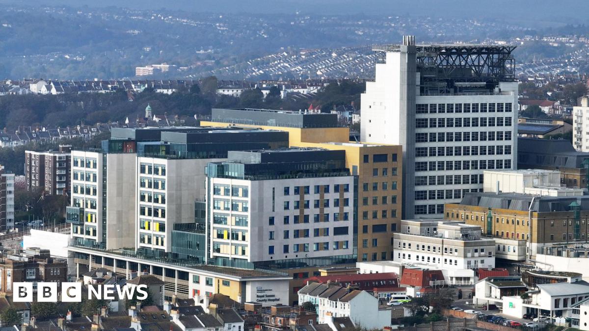 An aerial photograph of a building made of three multi-coloured arms with a tower to the right of it.
