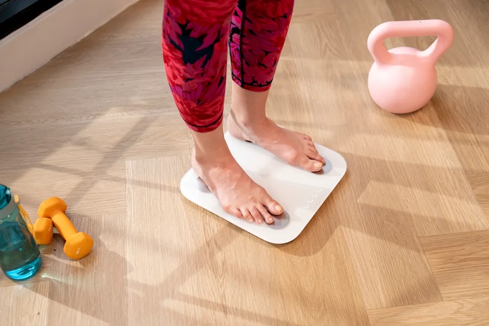 Close-up view of a young woman standing on a weighing scale.