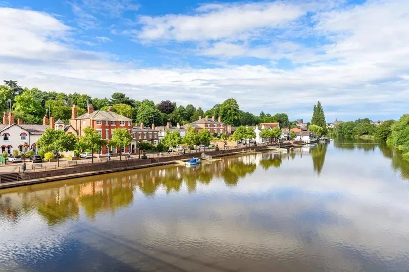 Residential buildings along a riverside street under blue sky with clouds on a summer day. Chester, England, UK.