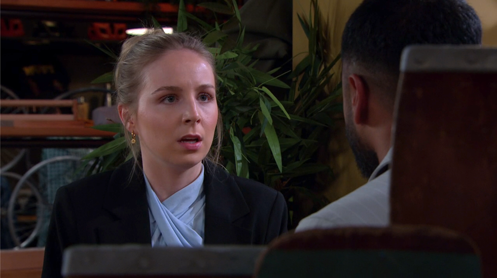 belle dingle sits across the table from kammy hadiq with an angered expression, emmerdale