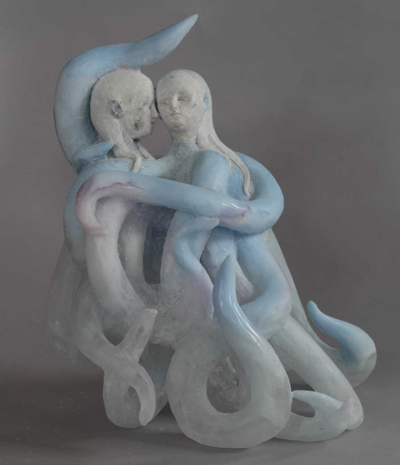 a glass sculpture of two young girls with blue sea monster-like tentacles