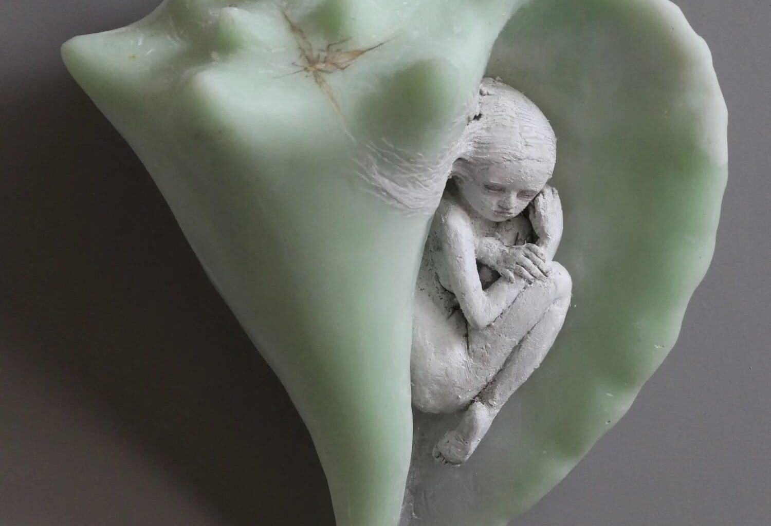 a small ceramic figure in a green shell