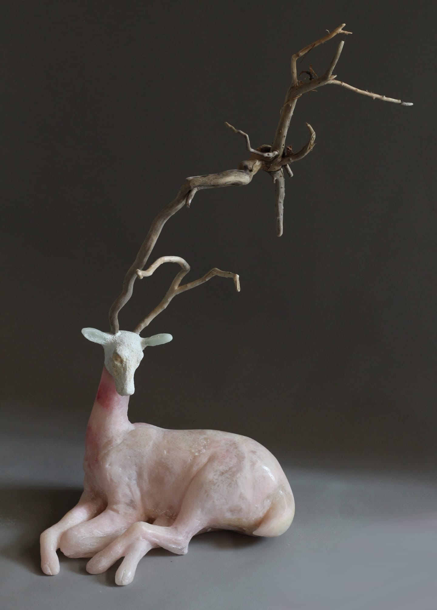 a glass sculpture of a deer with abstract, meandering wooden antlers