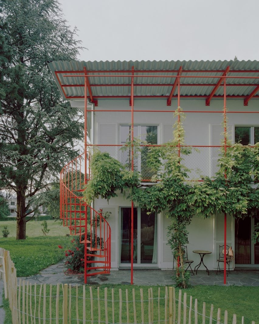 Two residential units connected by red steel staircase and balcony