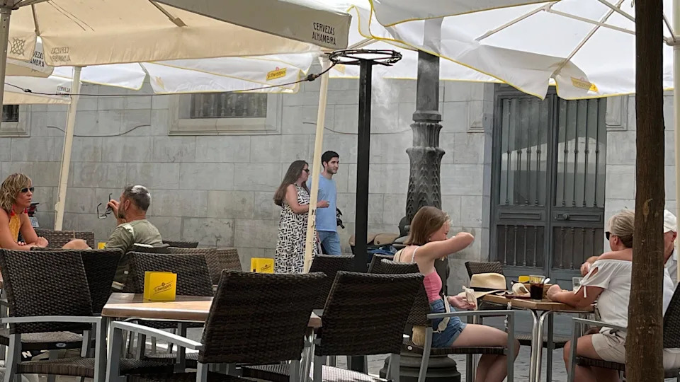 Customers sit beneath water misters in a cafe