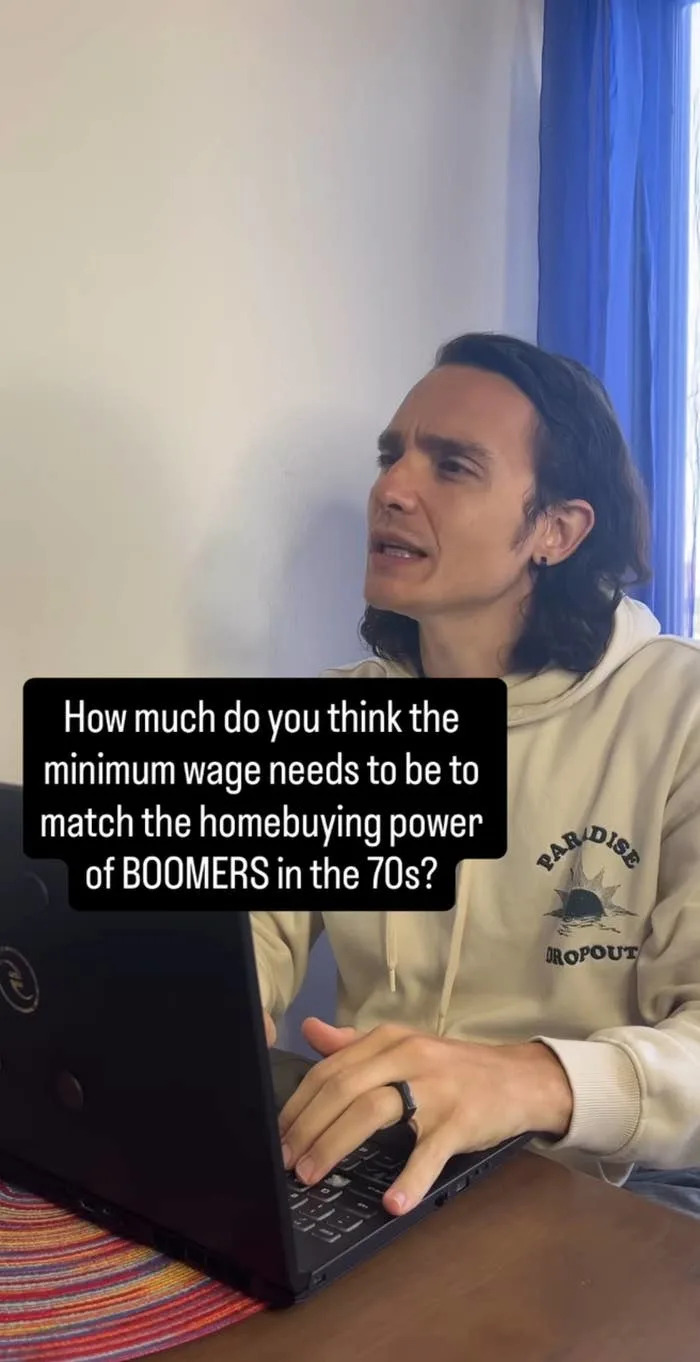 Person with long hair sits at a table using a laptop. Text asks: "How much do you think the minimum wage needs to be to match BOOMERS' homebuying power in the 70s?"