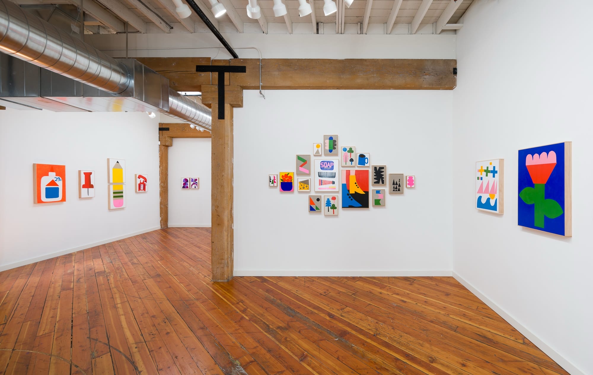 colorful works on white walls in a warehouse-style gallery