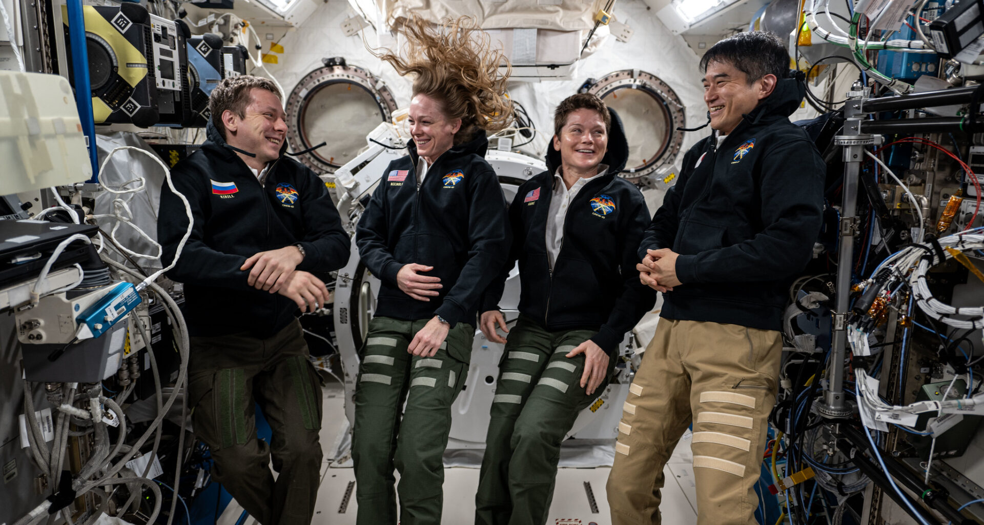 NASA's SpaceX Crew-10 members Kirill Peskov of Roscosmos, NASA astronauts Nichole Ayers and Anne McClain, and JAXA (Japan Aerospace Exploration Agency) astronaut Takuya Onishi share a light moment during a group portrait inside the International Space Station's Kibo laboratory module.