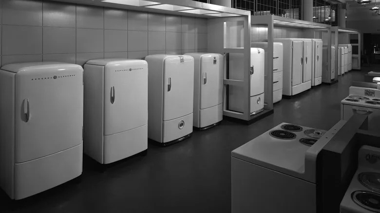 A black-and-white image of various refrigerators in a store