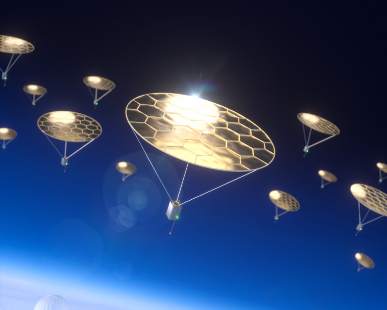 An artist's impression of multiple small devices with gold solar-powered 'parachutes' outside of the Earth's atmosphere