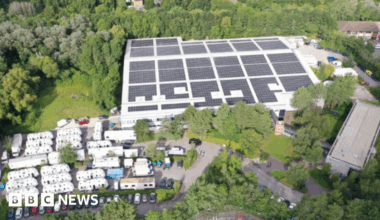 A view of The Bottle Yard Studios site from the air. It shows solar panels on the roof, trees, shrubbery and parked cars.
