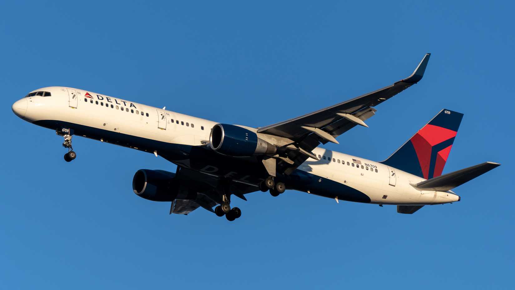 Delta Air Lines Boeing 757 in flight against clear blue sky.