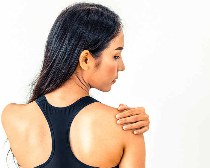 Woman in black sportswear touching shoulder, illustrating the doctor reveals 11 push-ups challenge for women’s health.