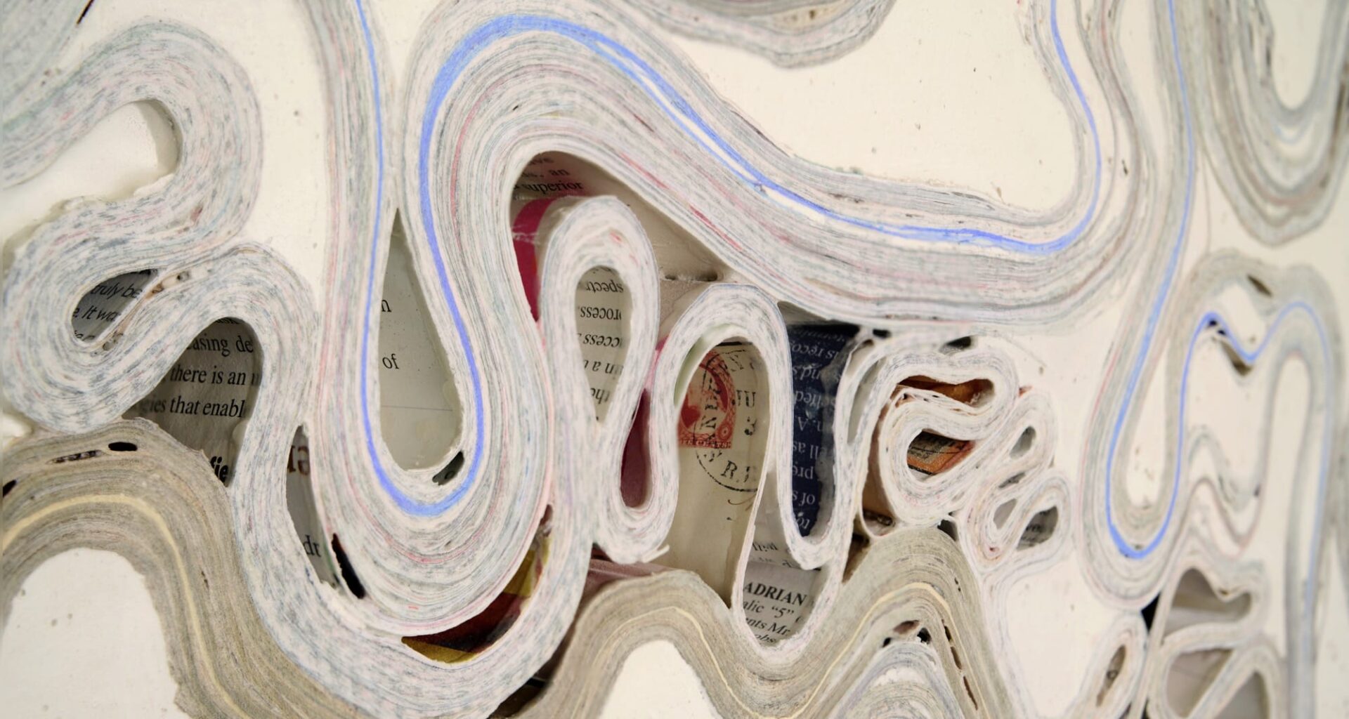 a detail of an abstract wall artwork by Jessica Drenk using repurposed junk mail and plaster in curving forms