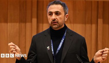 Suleyman dressed all in black, with an AI safety summit lanyard round his next, addresses the audience.